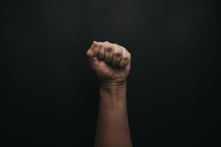 A powerful image of a raised fist against a dark background, symbolizing strength and unity.